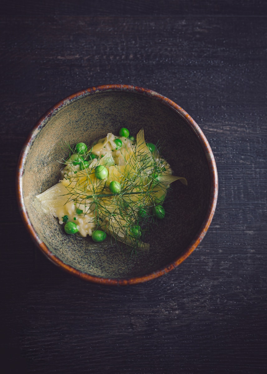 a bowl of food with peas on a wooden table